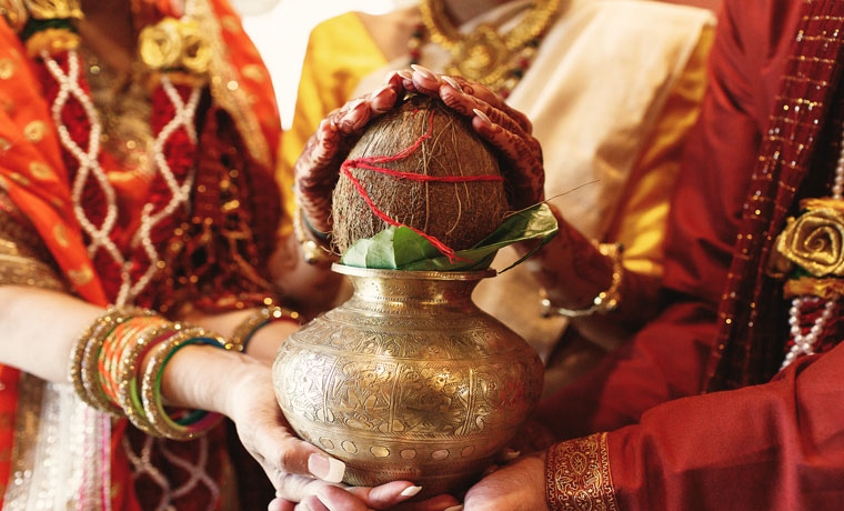 Indian bride's parents hold the bowl with coconut in her hands RVR school of potography