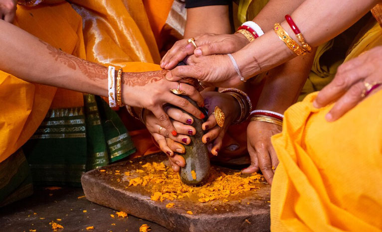 women grounding turmeric for halfsaree function